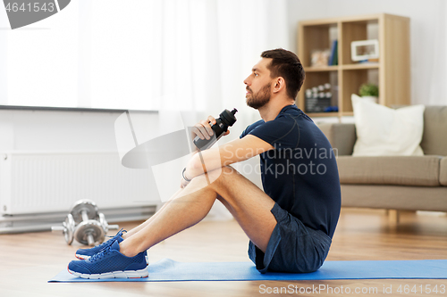 Image of man drinking water during training at home