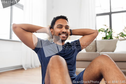 Image of indian man making abdominal exercises at home