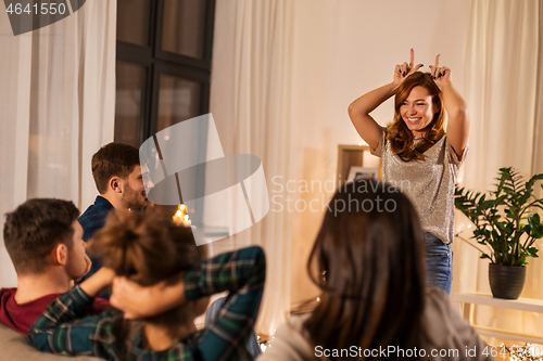 Image of happy friends playing charades at home in evening
