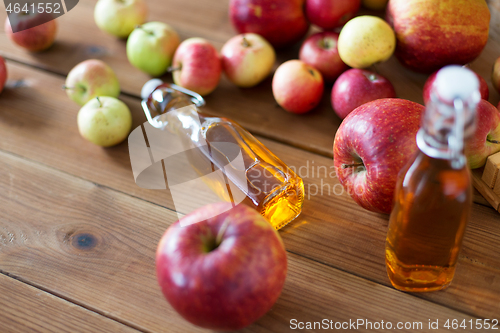 Image of bottles of apple juice or vinegar on wooden table