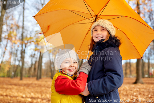 Image of happy children with umbrella at autumn park