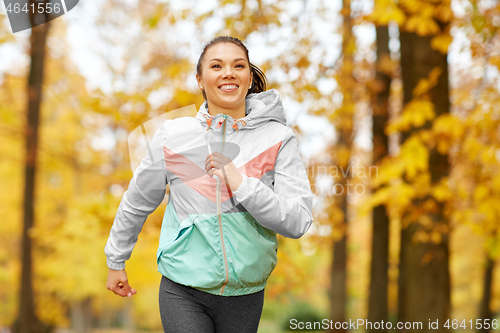 Image of young woman running in autumn park