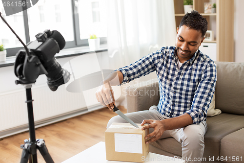 Image of male video blogger opening parcel box at home