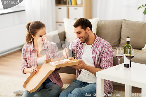 Image of couple with wine eating takeaway pizza at home