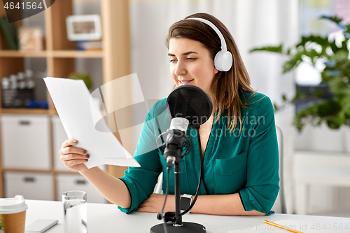 Image of woman with microphone recording podcast at studio