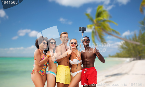 Image of friends taking selfie on beach and show thumbs up