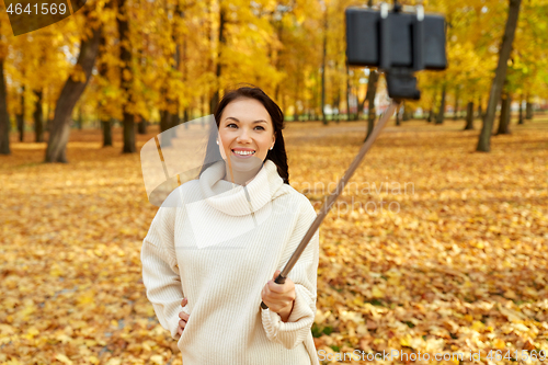 Image of woman taking selfie by smartphone at autumn park