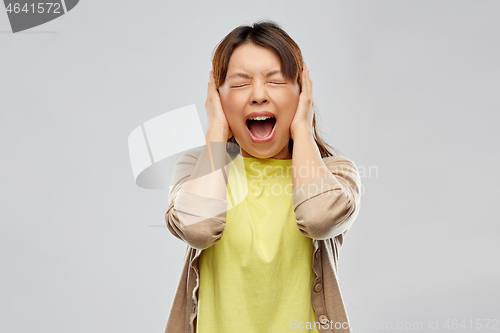 Image of stressed asian woman closing ears and screaming