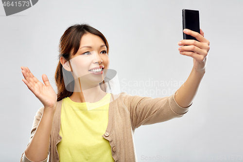 Image of asian woman taking selfie by smartphone