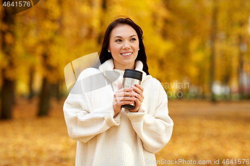 Image of woman with hot drink in tumbler at autumn park