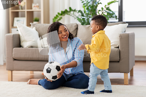 Image of mother and baby playing with soccer ball at home