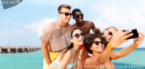 Image of happy friends taking selfie on summer beach