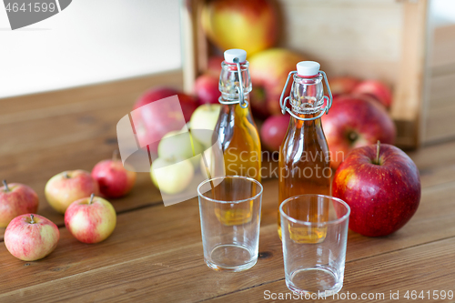 Image of glasses and bottles of apple juice on wooden table