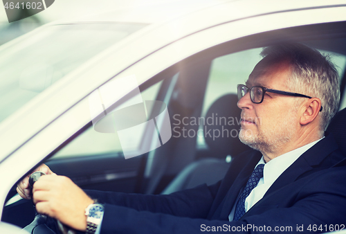 Image of happy senior businessman driving car