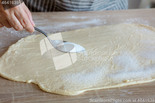 Image of sugar is poured on the yeast dough