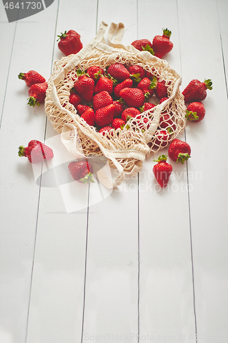 Image of Fresh strawberries in eco-friendly package on white wooden background. Vegetarian organic meal