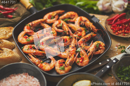 Image of Tasty appetizing roasted shrimps prawns with spices on pan with ingredients on rusty background