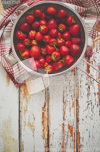 Image of Freshly harvested strawberries. Metal colander filled with juicy fresh ripe strawberries on an table