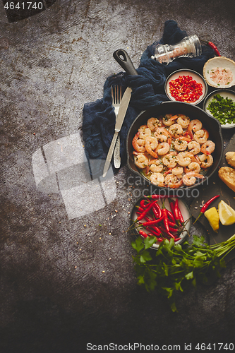 Image of Grilled shrimps in cast iron grilling pan with fresh lemon, parsley, chili, garlic white wine sauce