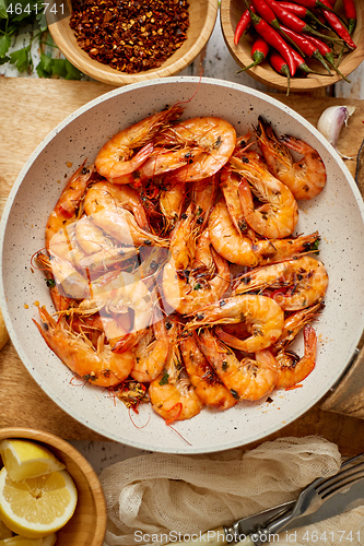 Image of Roasted Prawns on frying pan served on white wooden cutting board