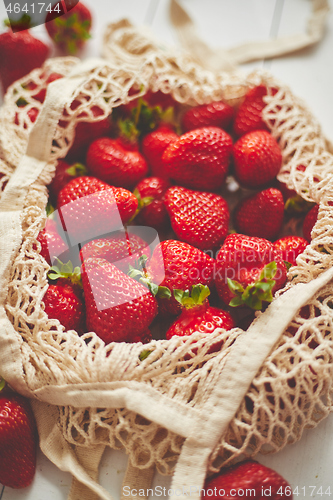 Image of Fresh strawberries in eco-friendly package on white wooden background. Vegetarian organic meal