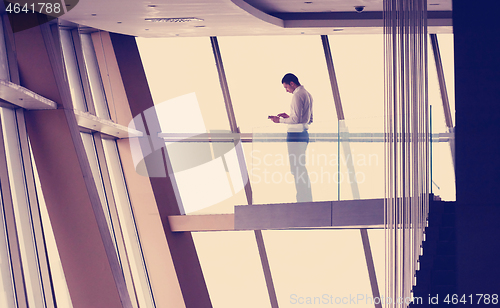 Image of young successful business man in penthouse apartment working on 