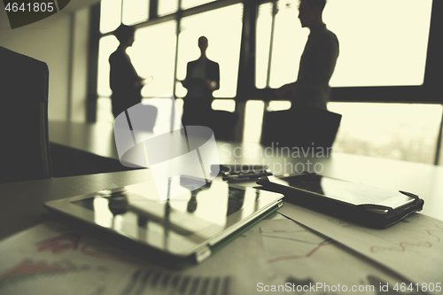 Image of close up of tablet, business people on meeting in background