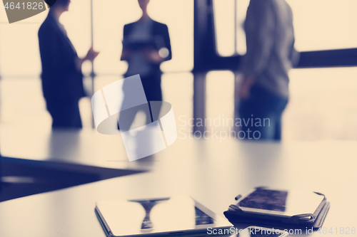 Image of close up of tablet, business people on meeting in background