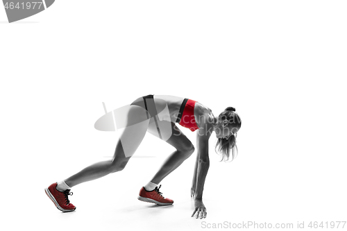 Image of Portrait of young sporty woman at starting block of race isolated over white background