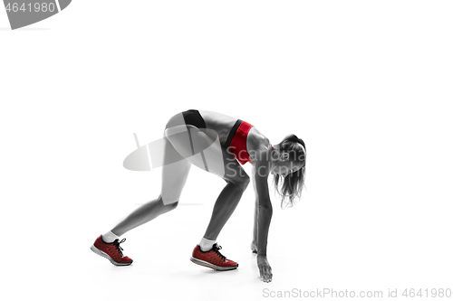 Image of Portrait of young sporty woman at starting block of race isolated over white background