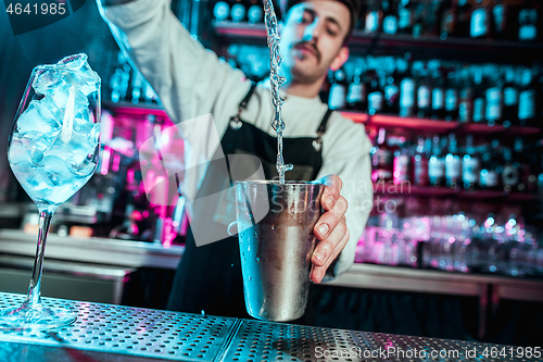 Image of Expert barman is making cocktail at night club.