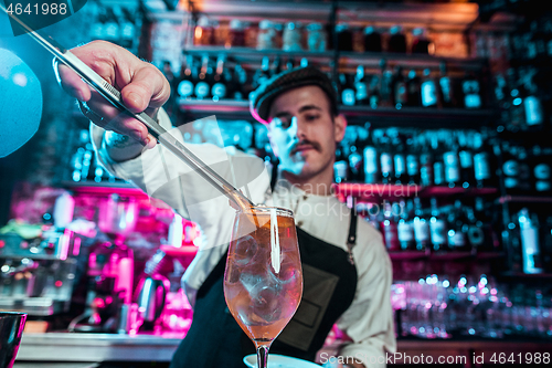 Image of Expert barman is making cocktail at night club.