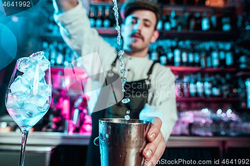 Image of Expert barman is making cocktail at night club.