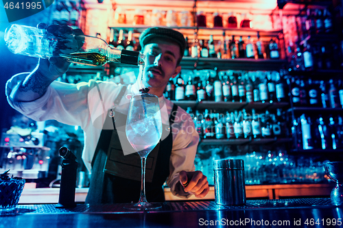 Image of Expert barman is making cocktail at night club.