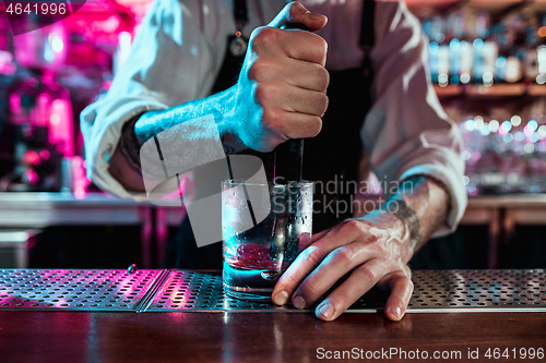 Image of Expert barman is making cocktail at night club.