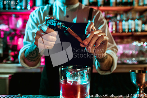 Image of Expert barman is making cocktail at night club.