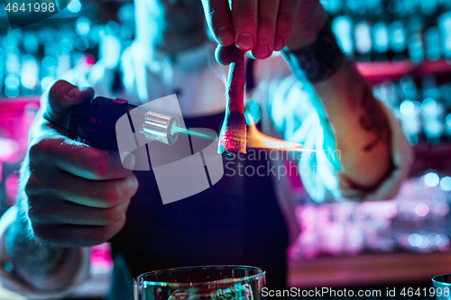 Image of Expert barman is making cocktail at night club.