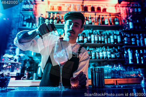 Image of Expert barman is making cocktail at night club.