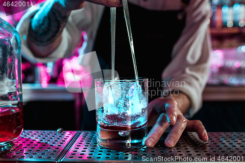 Image of Expert barman is making cocktail at night club.