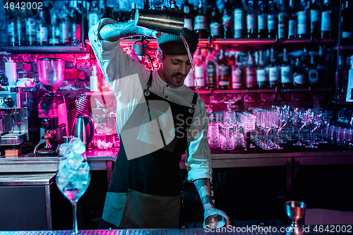 Image of Expert barman is making cocktail at night club.