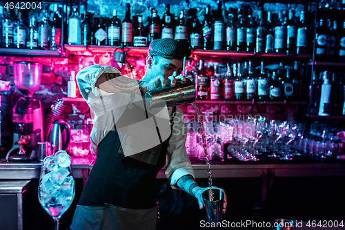 Image of Expert barman is making cocktail at night club.