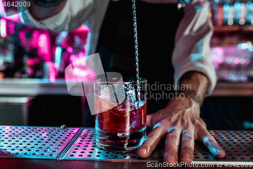 Image of Expert barman is making cocktail at night club.