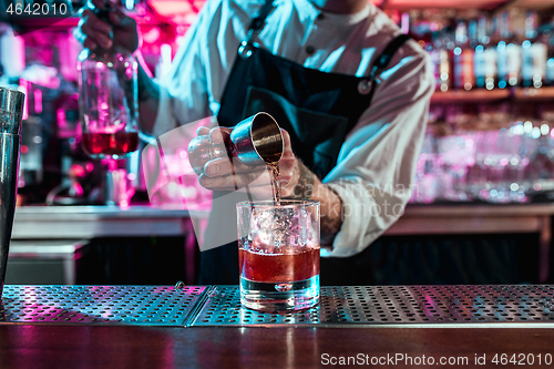 Image of Expert barman is making cocktail at night club.