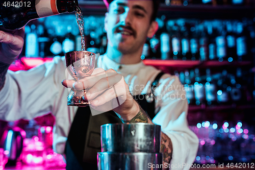 Image of Expert barman is making cocktail at night club.