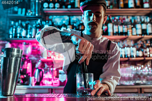 Image of Expert barman is making cocktail at night club.