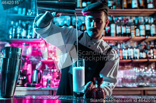 Image of Expert barman is making cocktail at night club.