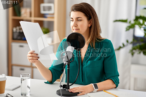 Image of woman with microphone recording podcast at studio