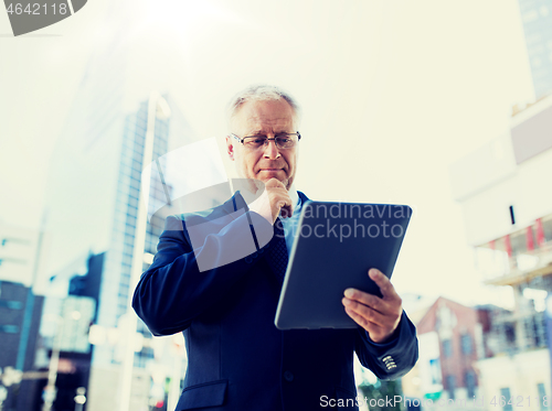 Image of senior businessman with tablet pc on city street