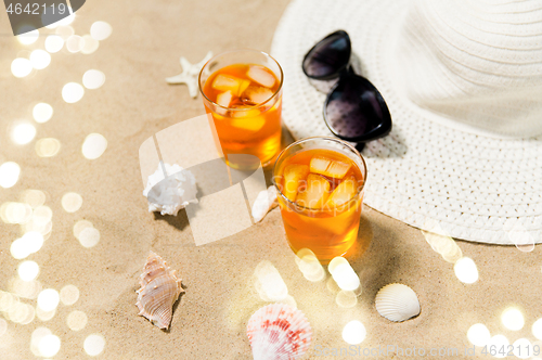 Image of cocktails, sun hat and sunglasses on beach sand