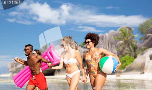 Image of friends run with beach ball and swimming mattress